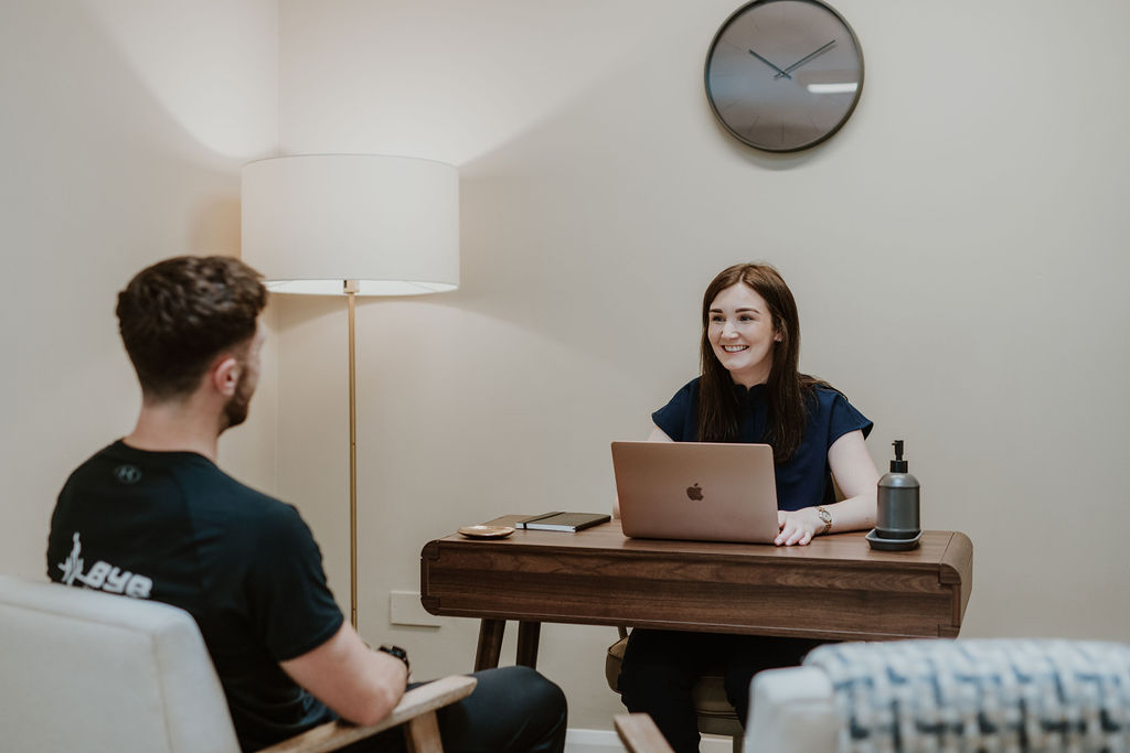 Osteopath Hannah Hilton taking the case history of a male patient